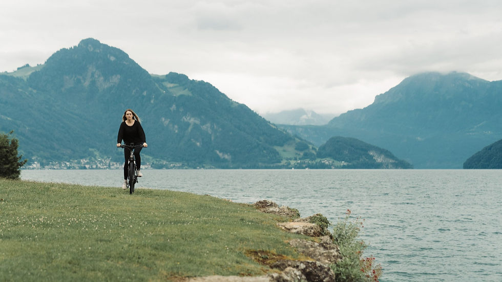 Woman cycling along a lakeside path at Chenot Palace Weggis with panoramic views of the Swiss Alps in the background