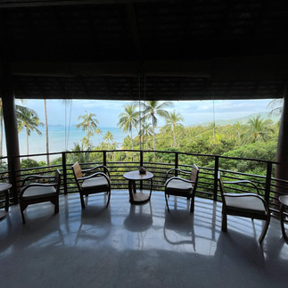 Covered outdoor seating area with chairs and a sea view at Kamalaya Wellness Sanctuary.