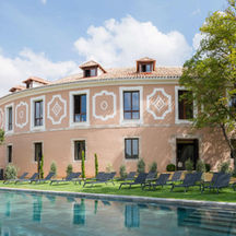 Outdoor thermal pool at Castilla Termal Brihuega, with elegant heritage-style architecture and sun loungers in a peaceful garden setting