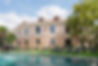 Outdoor thermal pool at Castilla Termal Brihuega, with elegant heritage-style architecture and sun loungers in a peaceful garden setting