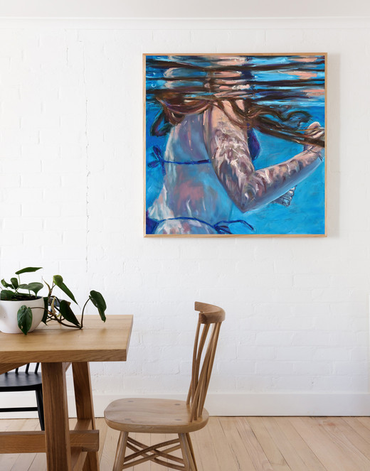 painting of a woman with long hair, swimming underwater. displayed in a living room.