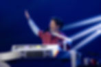 Charlie Puth at a Yamaha keyboard, singing with one arm raised on a blue-lit stage.