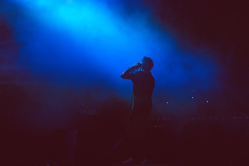 Silhouetted singer on a blue-lit stage holds a microphone, creating a moody concert scene.
