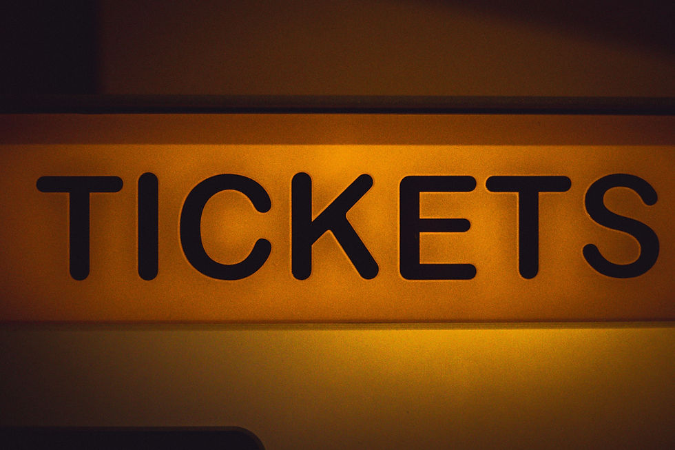 Close-up of a warm orange sign with the word TICKETS in bold black letters, likely at a ticket booth or entrance.