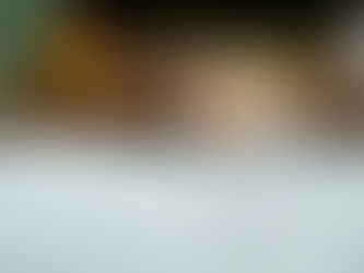 Frozen cocktail with a chili-rimmed glass and lime slice on a white surface. Blurred background with pineapple, knife, and cutting board.