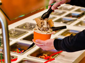 hand holding cup of frozen yogurt with toppings