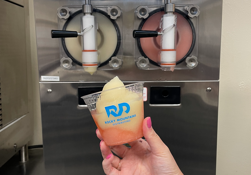 yellow and pink frozen beverage slush in a cup in front of machine