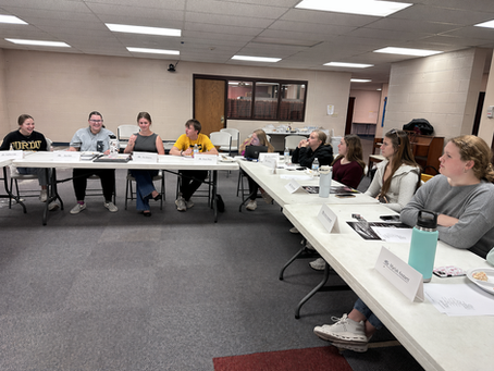 This picture features 5 members of the YPC leadership team, as well as 4 members of the YPC. They are sitting in an L formation during a monthly meeting.