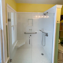 Tub to shower conversion with new Onyx surround, low threshold base, built in corner seat, recessed caddy, brushed nickel shower fixtures, grab bars, and pivot shower door with clear glass. 