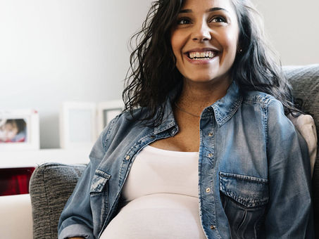 Smiling pregnant woman at home, representing a baby shower celebration for parents-to-be.