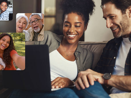 Couple smiling while watching a group video gift on a laptop, with video messages from friends and family appearing on screen.