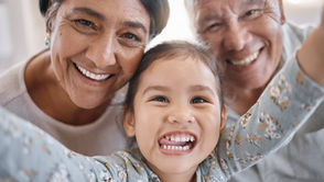 Grandparents taking a happy selfie with their granddaughter at home.