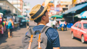 Solo traveler with backpack looking out over a scenic river landscape at sunset.