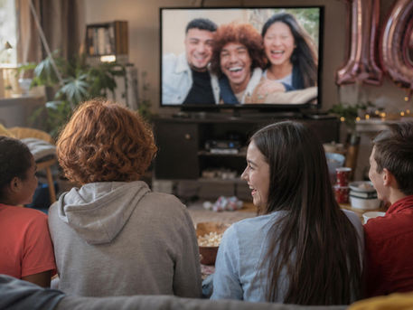 Teens watching a Sweet 16 birthday video montage on TV during a birthday party.