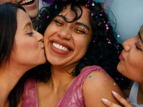Friends celebrating a 21st birthday, smiling and hugging with confetti.