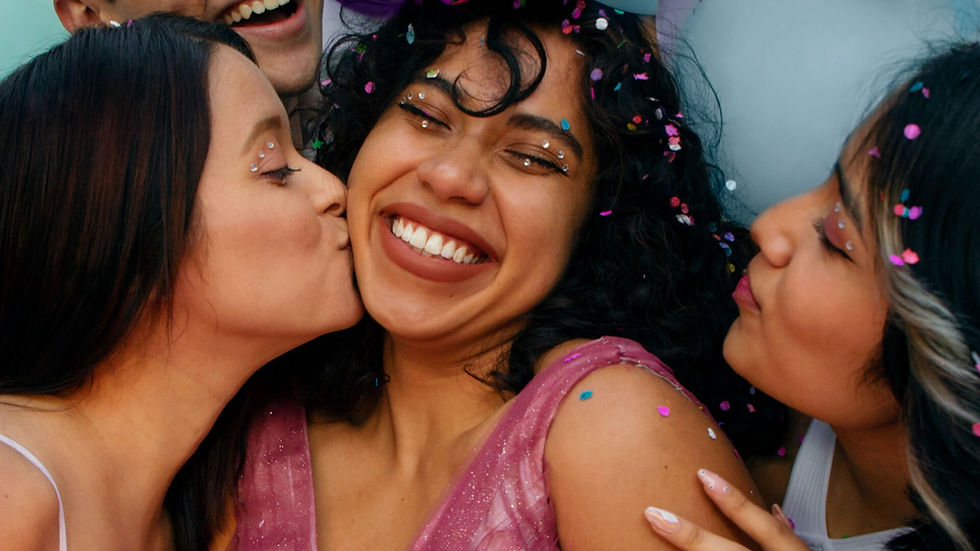 Friends celebrating a 21st birthday, smiling and hugging with confetti.