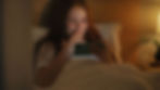 Woman resting in bed at home, touched as she watches a Get Well video from friends and family on her phone.