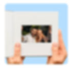 Hands holding an open video book featuring a screen displaying a smiling couple taking a selfie. The sleek, white design of the video book emphasizes its modern and elegant appearance, providing a unique and interactive way to preserve and share wedding memories.