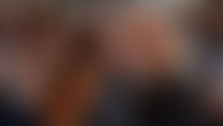 Woman laughing with coworkers while watching a retirement video together in an office.