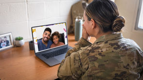Deployed service member watching a family video message on a laptop.