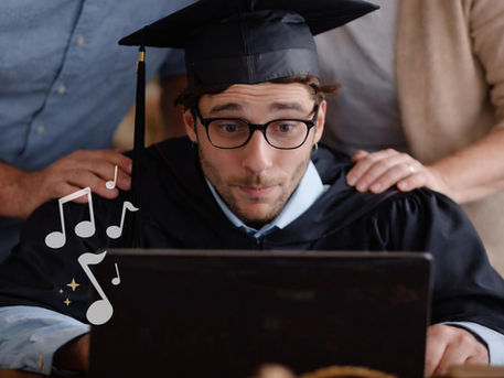Graduate watching a personalized graduation video on a laptop with family behind him, reacting to a meaningful message.