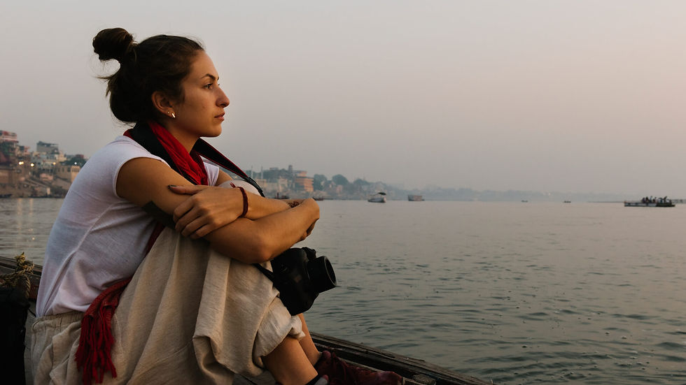 Solo traveler sitting on a boat at sunset, reflecting while away from home.