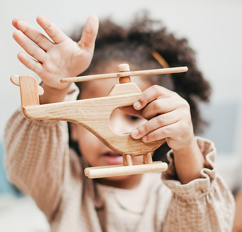 young girl playing with wooden helicopter