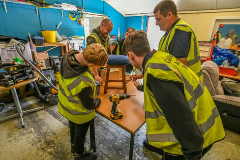GAT volunteers working on a stool in a renovation workshop. 
