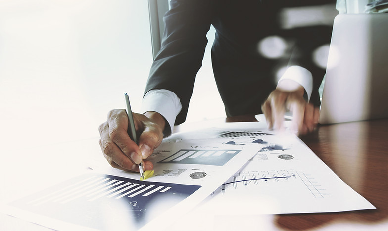 A suited individual is writing on papers, concentrating on their work at a desk