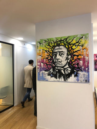 Colorful street art portrait of Salvador Dalí with tree branches coming from his head, displayed in an office hallway