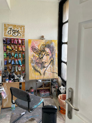 Abstract portrait painting with butterfly details in an artist's studio, surrounded by art supplies
