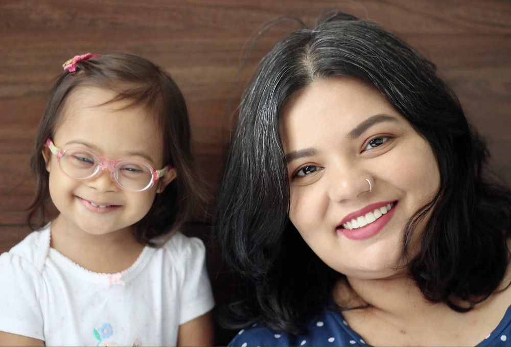 An Indian woman with her daughter who has Downs syndrome smiling for the camera