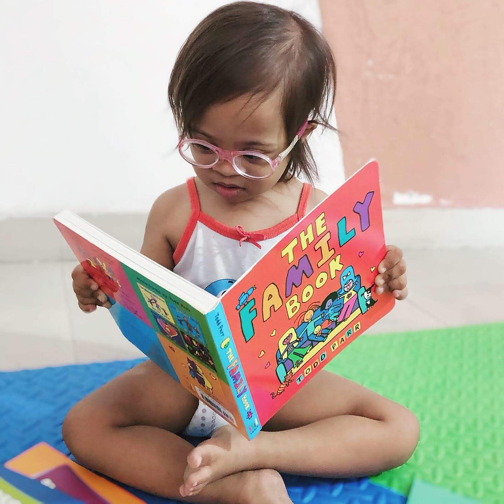 Indian Toddler with Down Syndrome reading a book