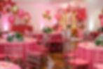 Salão de festas decorado com balões cor-de-rosa e dourados.