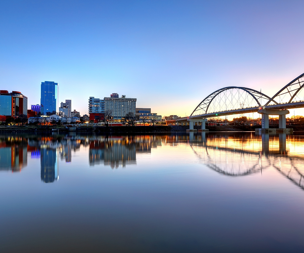 Ground-level view of the Arkansas River, Broadway Bridge, and downtown buildings in Little Rock, Arkansas.