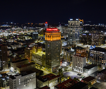 Aerial skyline of Birmingham, Alabama at night showing apartment buildings, condominiums, office buildings, and parking garages.