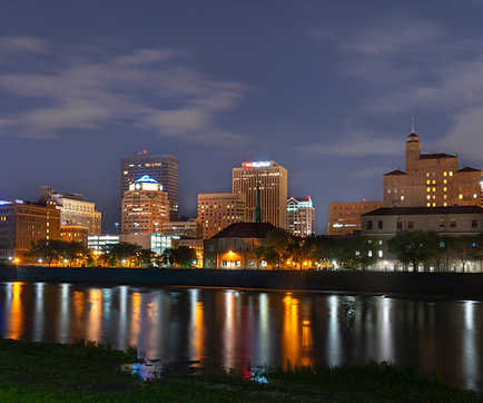 City skyline of downtown Dayton, Ohio and the adjacent river at night.
