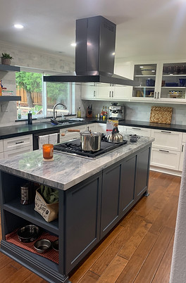 Custom grey kitchen cabinetry work with marble countertops, kitchen island with hood