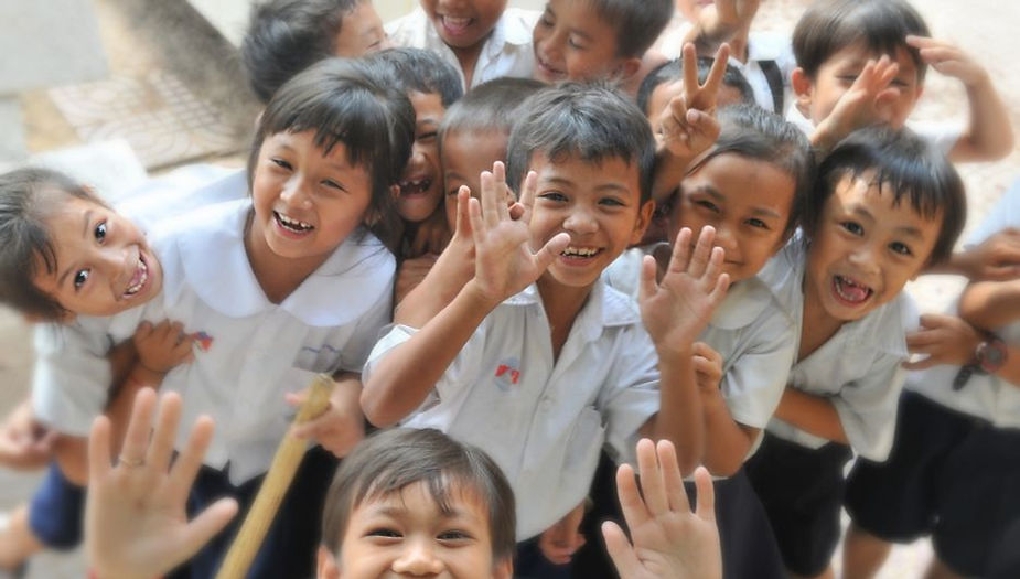 Group of joyful children waving in a school setting.