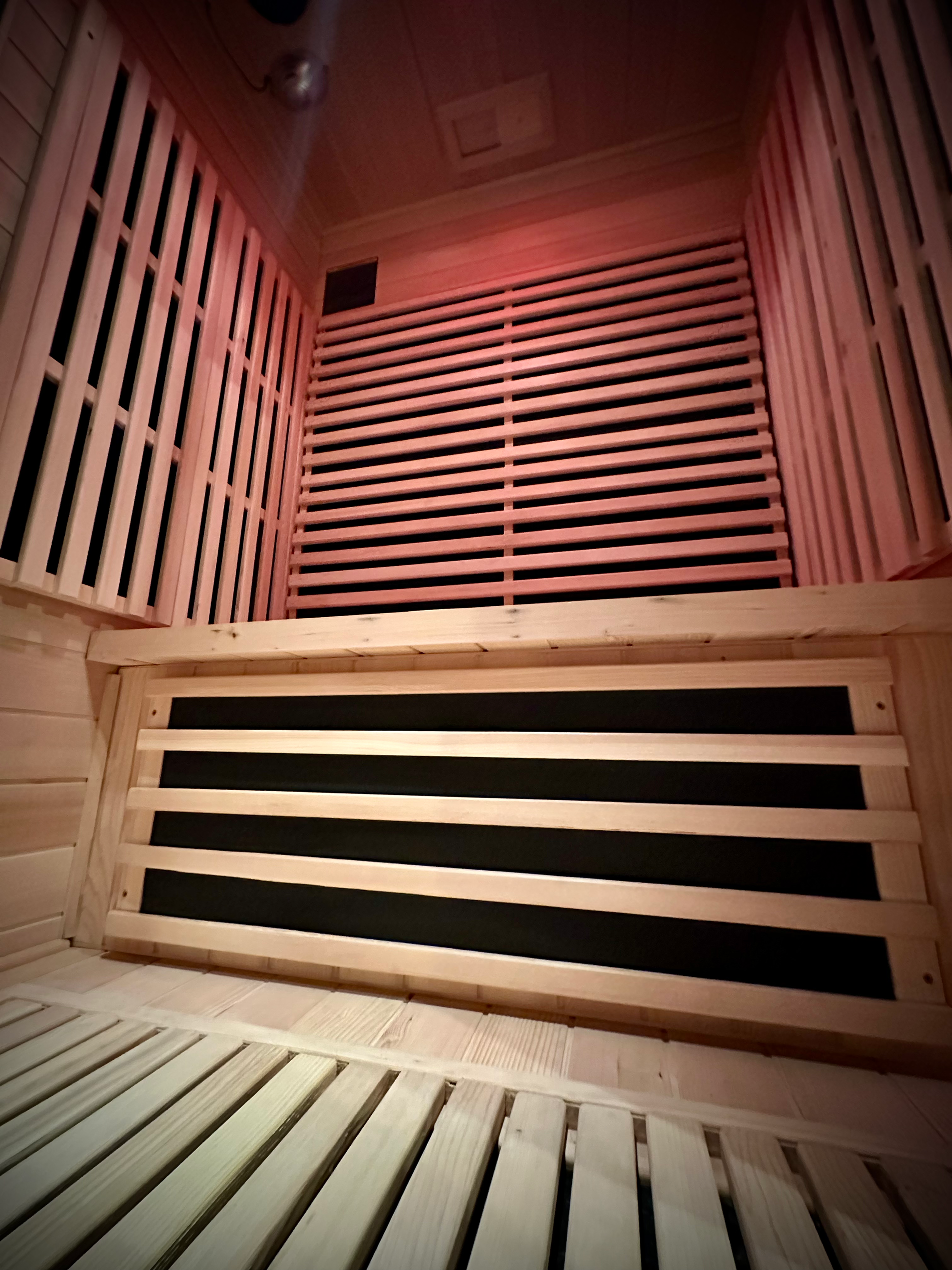 Intérieur d'un sauna en bois avec lumières rouges. EvasionPrivée pour détente et relaxation.