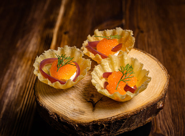 En förrätt med Kalix löjrom serveras på ett träunderlägg.