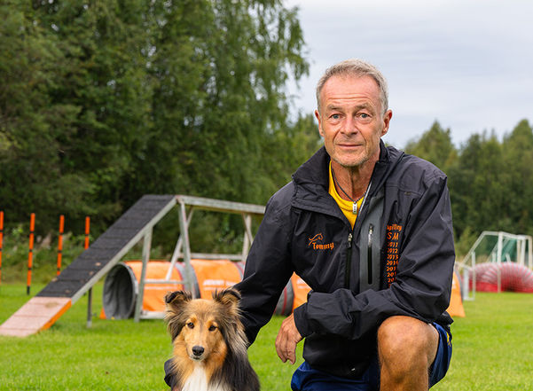 En man med hund på en agilitybana