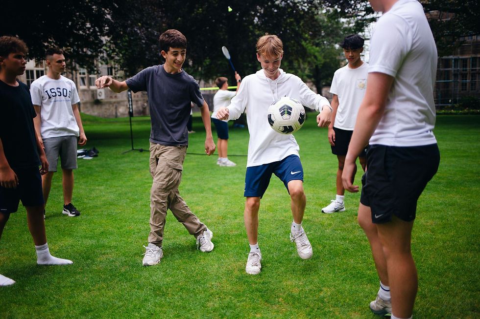 ISSOS students playing football together on a grassy field.