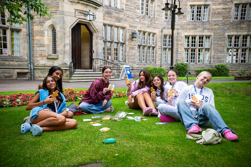 ISSOS students sitting on the lawn at the University of St Andrews, holding gingerbread men and enjoying snacks outside the historic quad.