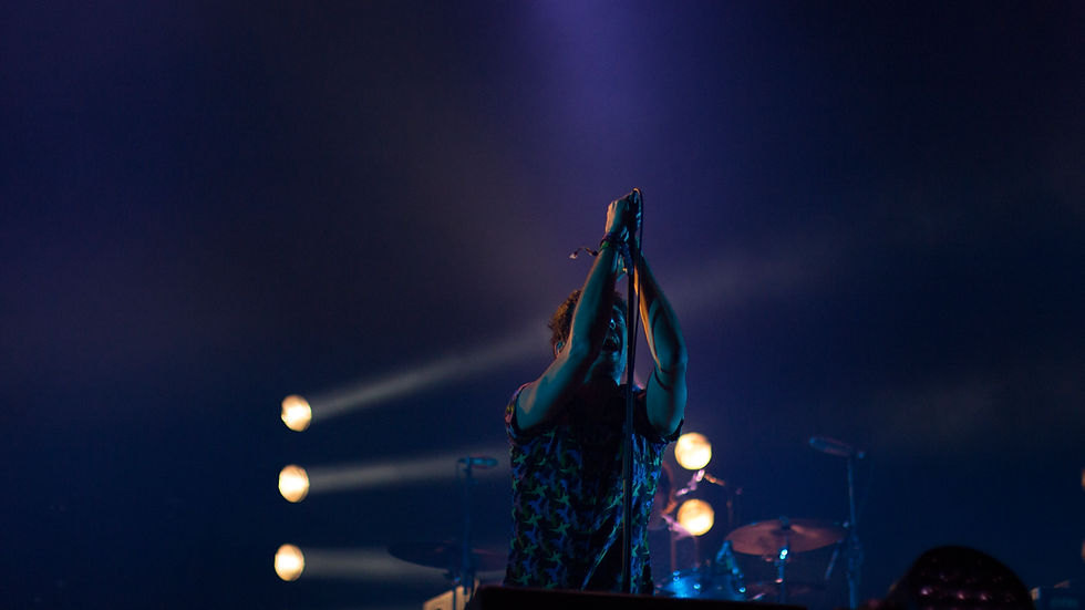 Singer on stage under blue and white stage lights.