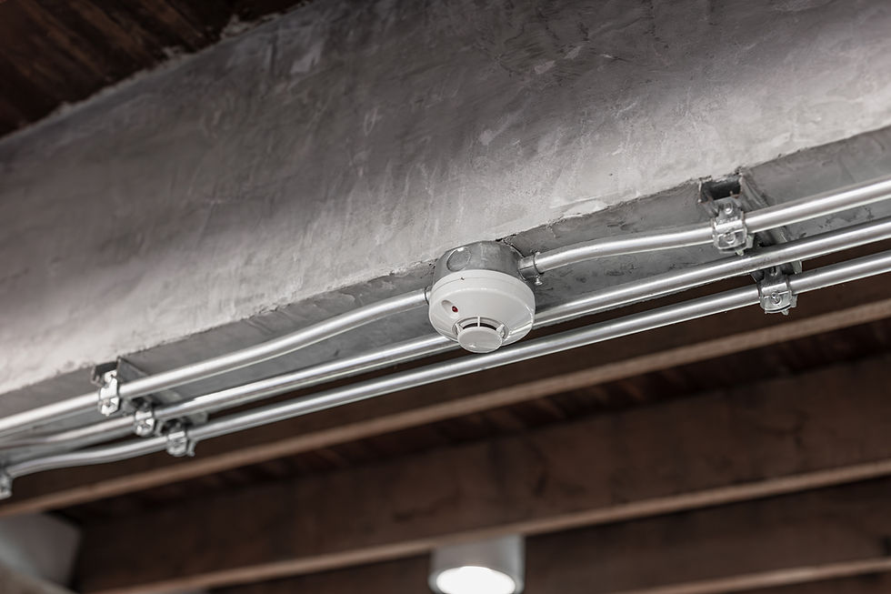 White smoke detector on ceiling, part of the Fire & Life Safety system.