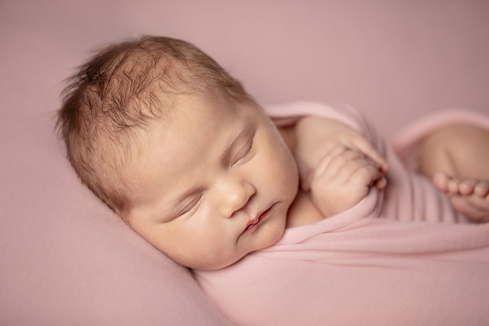 Ritratto emozionante e tenero di una neonata di 10 giorni mentre dorme con capelli chiari e pelle rosea realizzato con accessori abbigliamento e wrapping morbido e delicato rosa