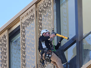 worker with abseiling gear repairing building