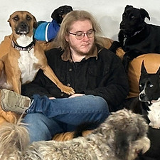 Theo sitting on a couch with dogs surrounding him