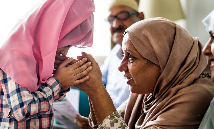 Young girl kissing a woman's hand, family moment, cultural tradition.